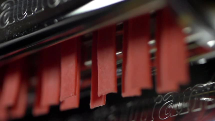Pasta noodles coming out of a machine
