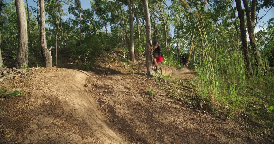 Two people racing mountain bikes around a dirt corner