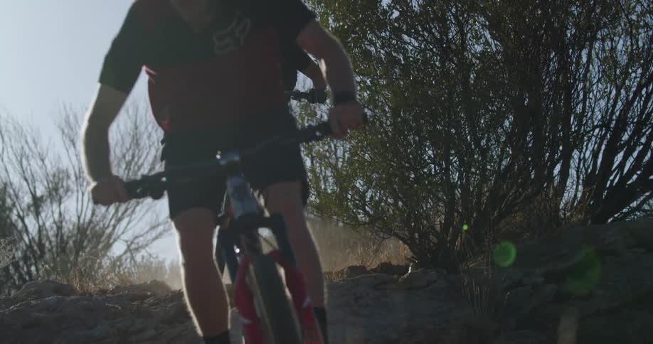 Two people mountain bike down a hill