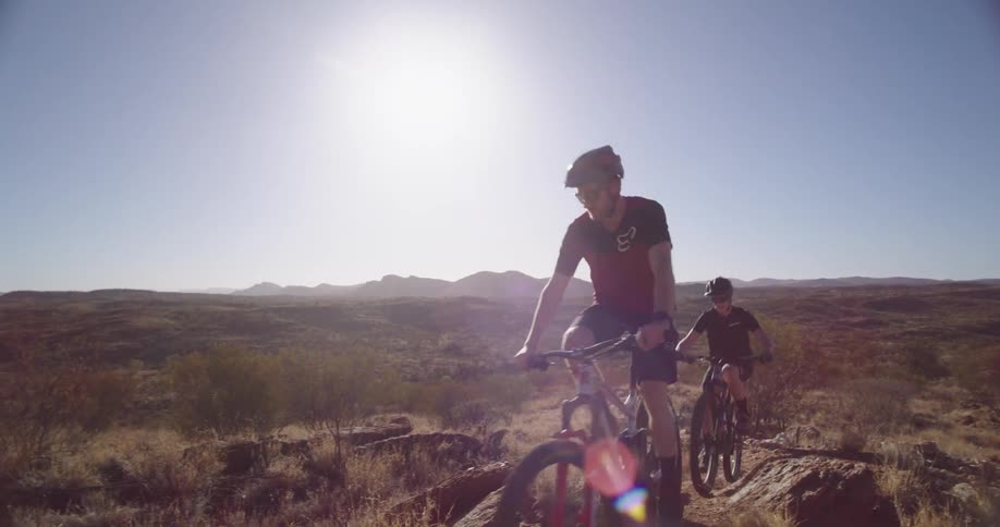 A man and woman mountain biking on desert trail