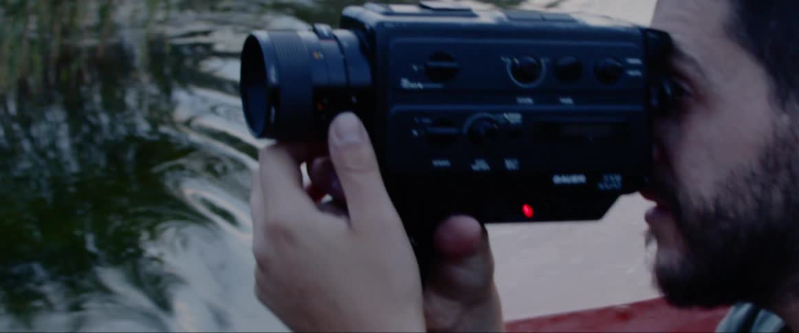 A man uses a video camera while floating on water in a boat