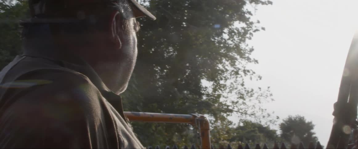 Man in baseball cap driving farm vehicle