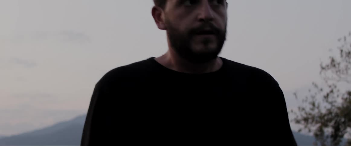 Bearded man outdoors walks while looking around nervously