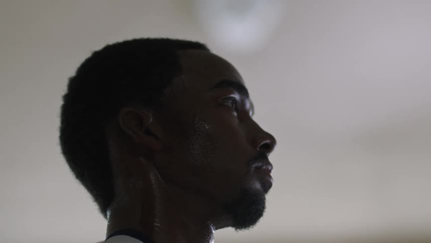 A man stands inside and looks straight ahead