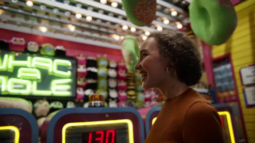 Two young women laugh and talk in front of carnival game booth