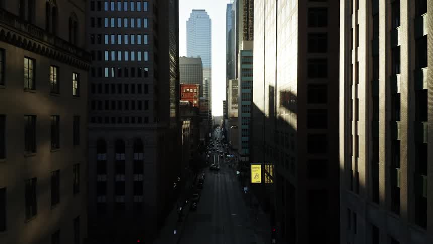 Aerial view of a city street surrounded by tall buildings at sunrise