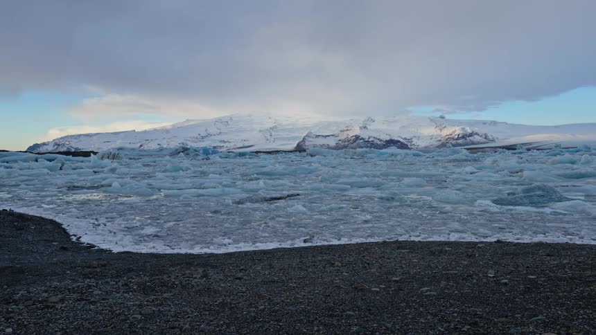 A glacier with a snow covered mountain in the background