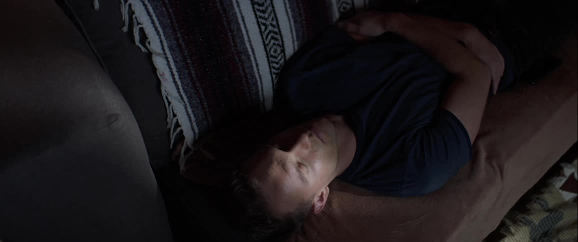 A white man lies on a couch and sleeps
