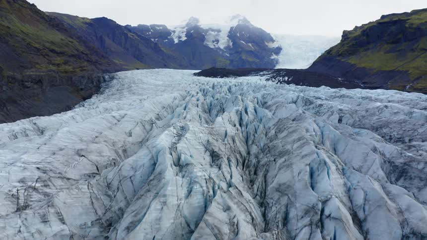 Ice covers a river that flows between the mountains