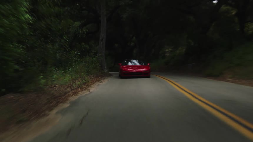 Red sports car driving fast on a windy road through the mountains