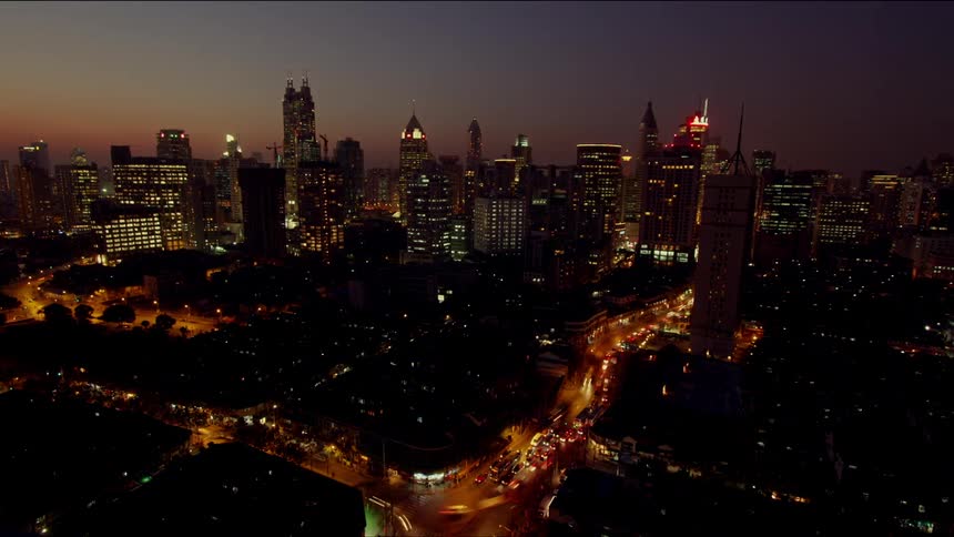 Cars travel on city streets at night with lights on causing a glow