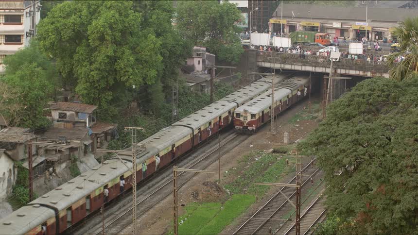 Trains pass under bridge with dense traffic