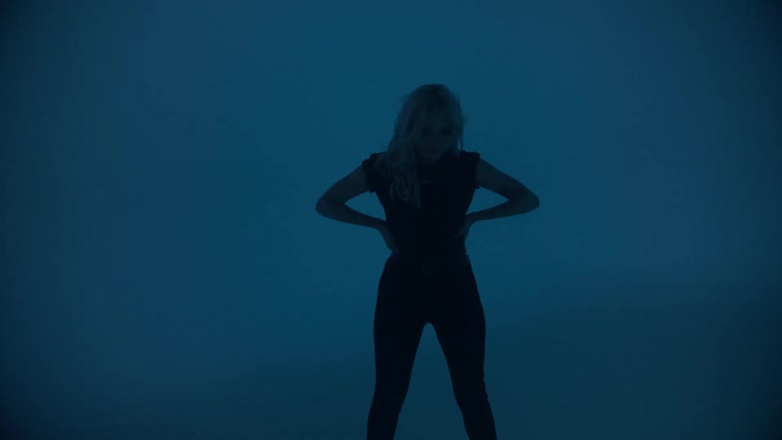 Woman stands in dark empty space with strobe effect