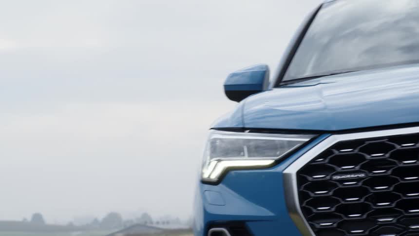 A blue car drives down a road