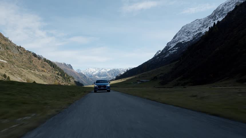 A car drives down a street through the mountains