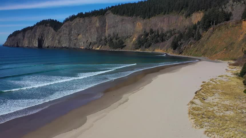 Deep blue ocean and beach next to tall cliffs