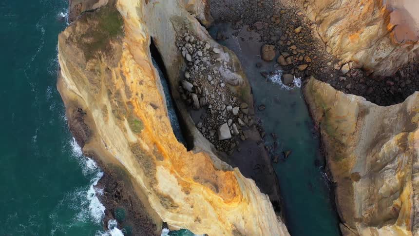 An aerial view of an ocean and cliffs is displayed