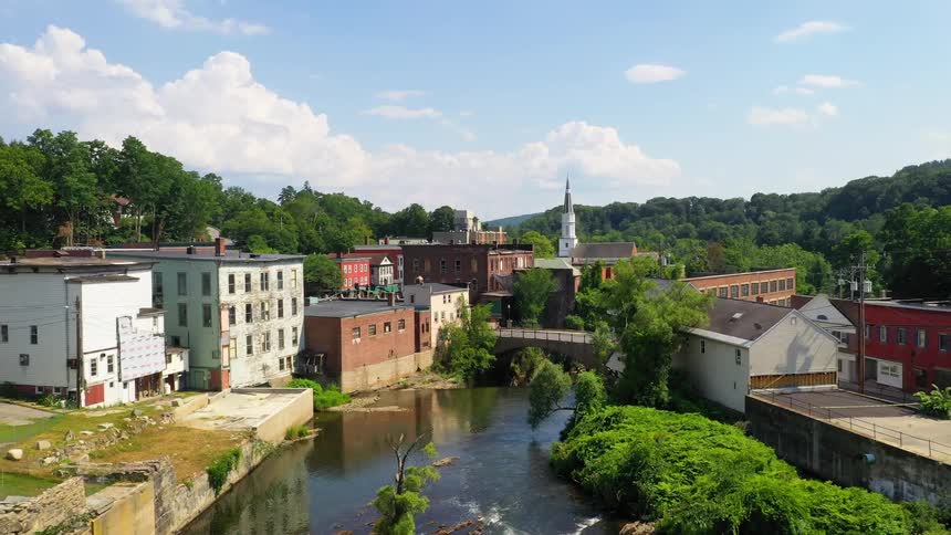 A river running through a small run down town surrounded by forest