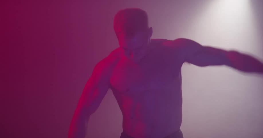 Man working out with dumbbells in hazy room with pink lighting