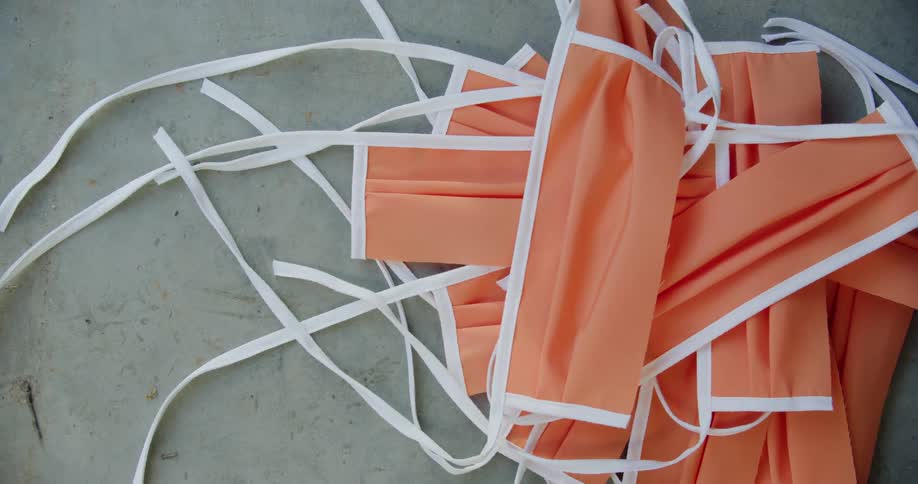 A face mask drops onto a pile of other face masks on the floor