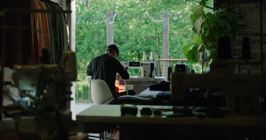 A man sits and sews with his machine