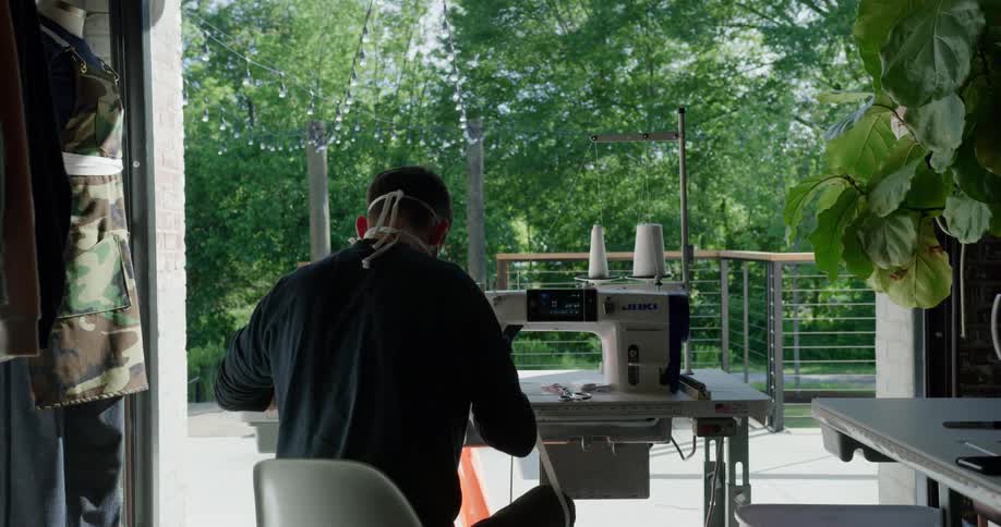 Man using sewing machine to make masks