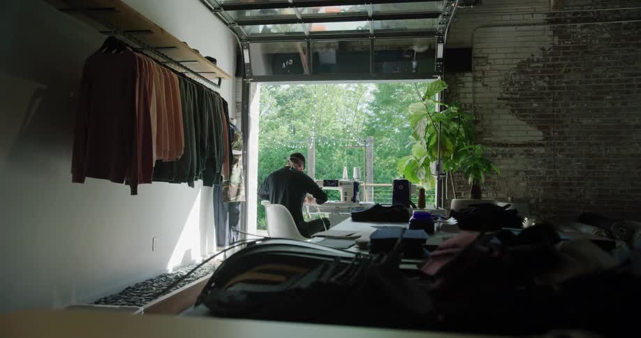 Man sits at table sewing on sewing machine