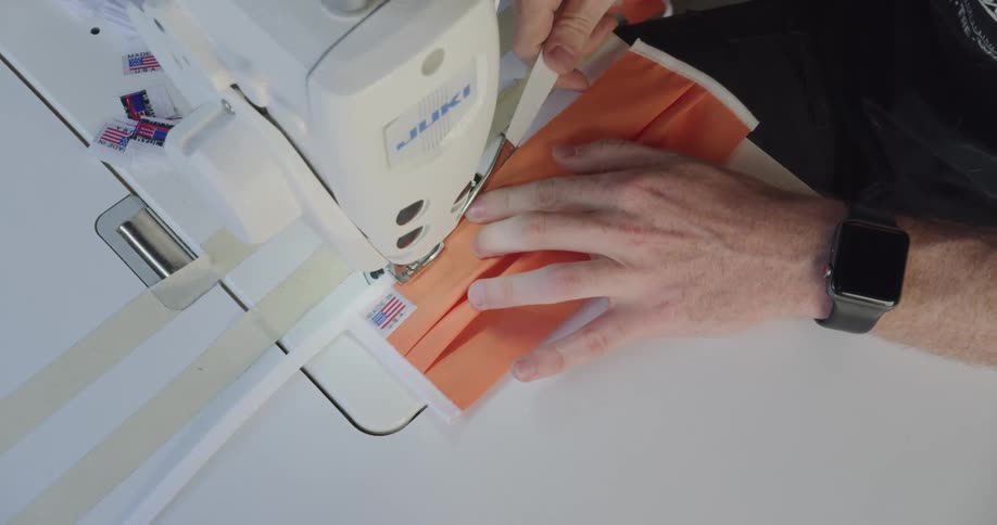 A man using a sewing machine to make a face mask