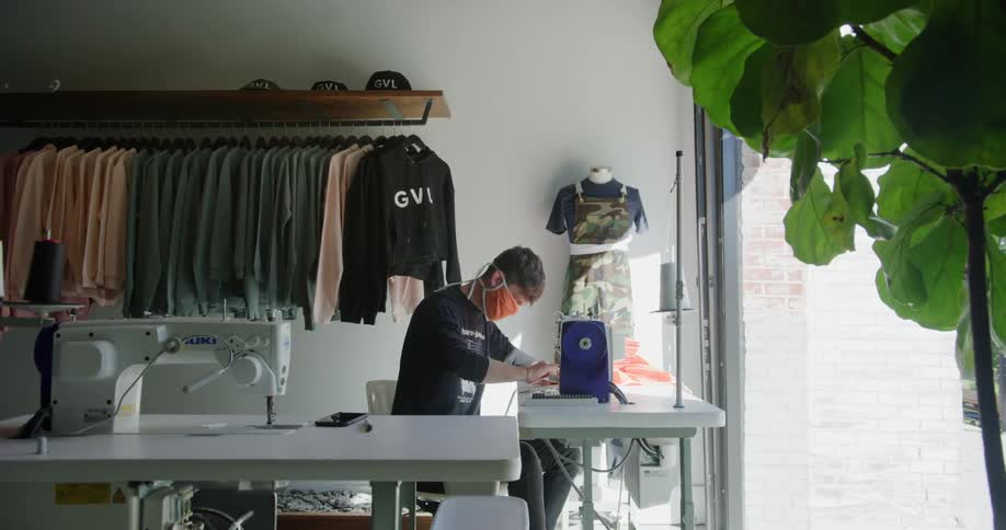 Man in store using sewing machine to make masks