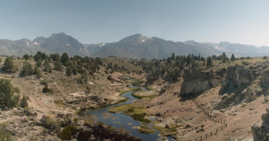 A shallow river runs through a shallow canyon in a desert