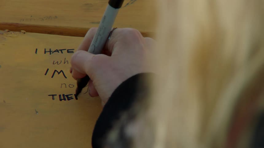 Young woman writes note on yellow wood