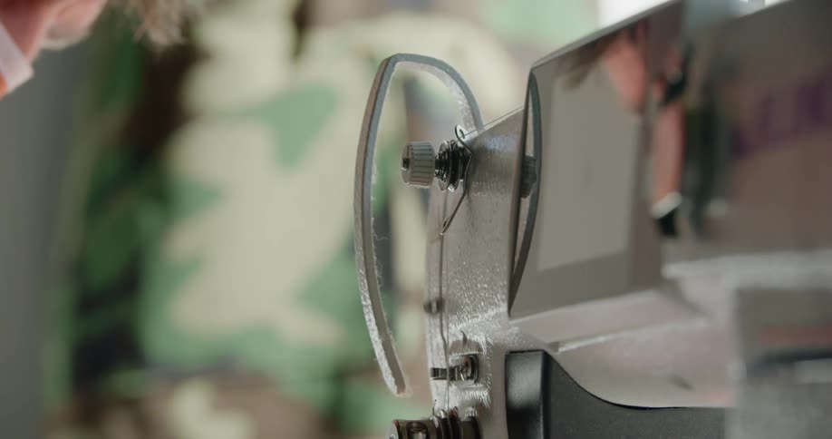 A man in a face mask operates a sewing machine