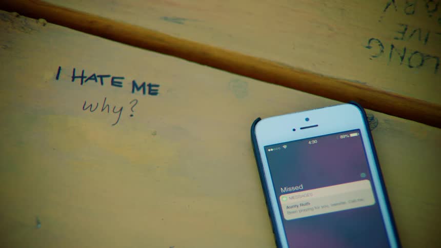 A smartphone sits on painted wood with words written on them