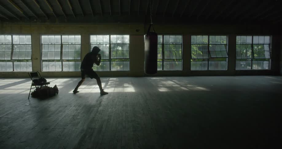 A man shadow boxes in an empty room