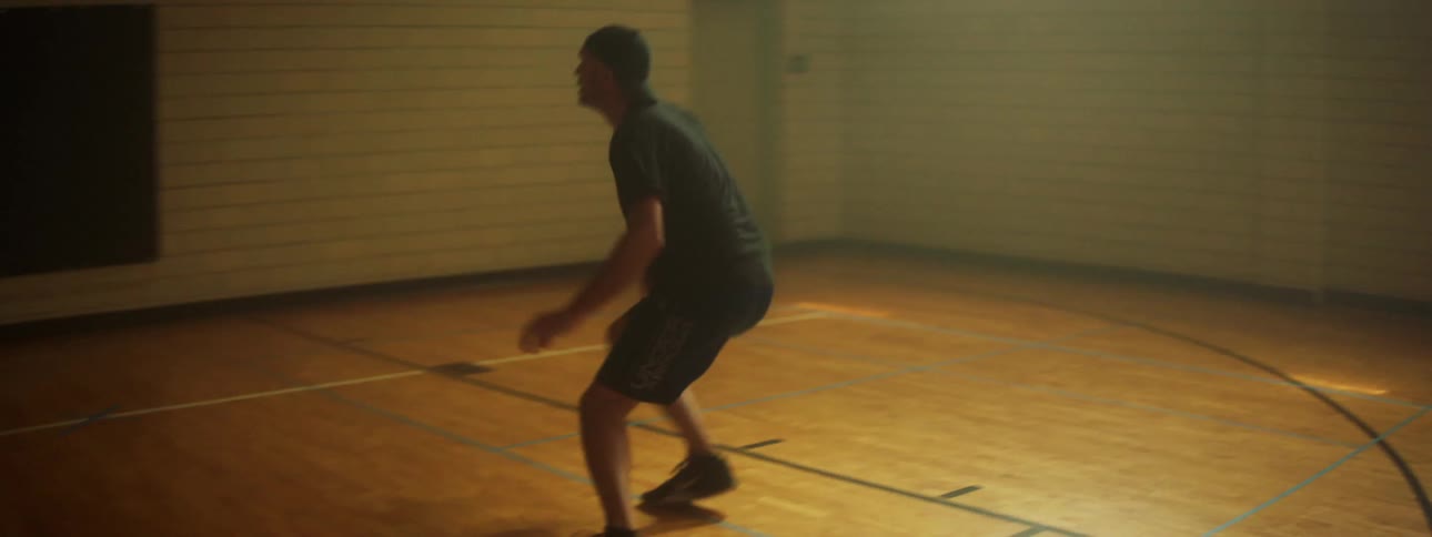 A plays basketball by himself in a gymnasium
