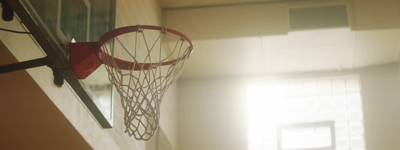 A basketball flying through the net of a basketball hoop before a second shot bounces of the backboard