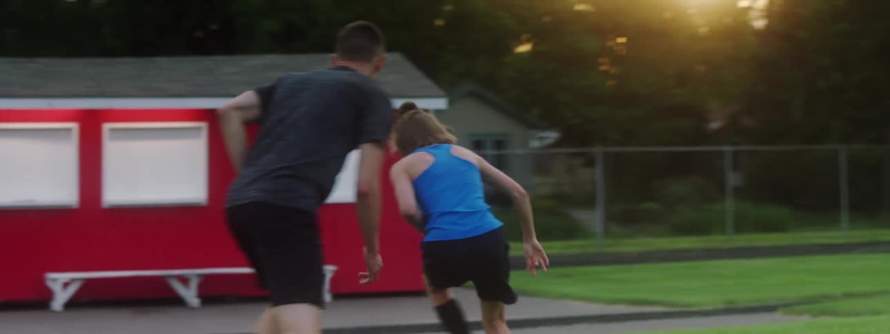 A brother and sister practice soccer on a soccer field