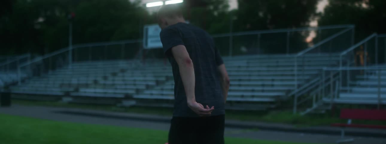 A brother and sister practice with a soccer ball in a soccer stadium