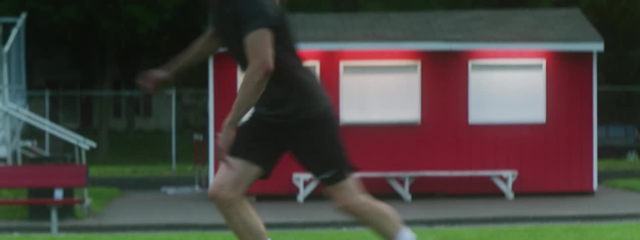 Man dribbles soccer ball on field in evening