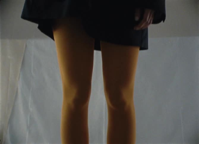A black woman stands on a pedestal and models