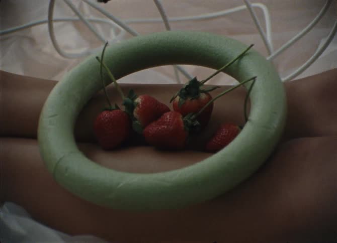 A styrofoam hoop filled with strawberries is on a womans legs