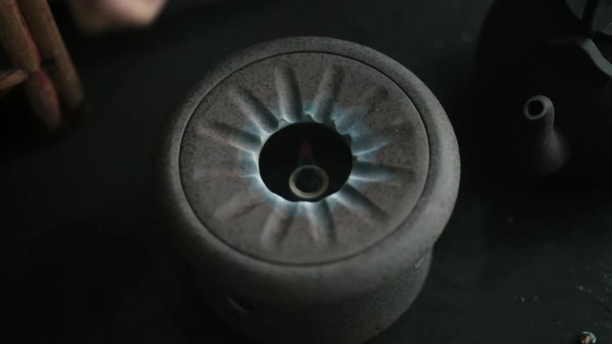 A person lights a metal hot plate pilot with a lighter