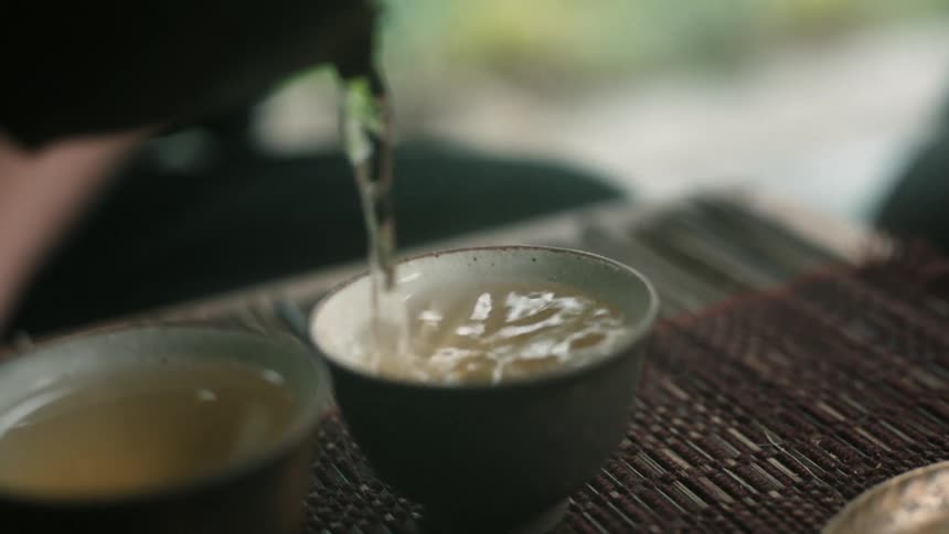 A person pours water in mugs to make tea