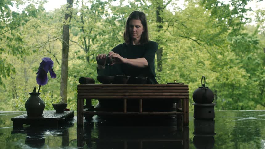 A woman stands at a podium outdoors and pours water in to bowls