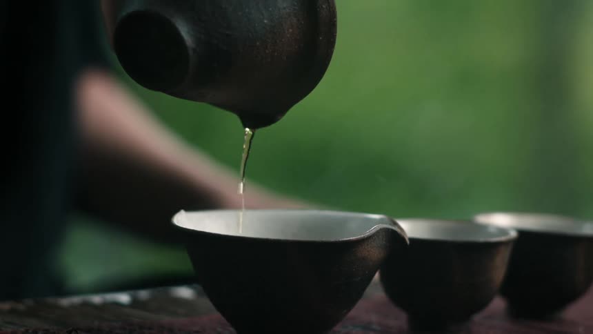 A person is filling up small tin cups