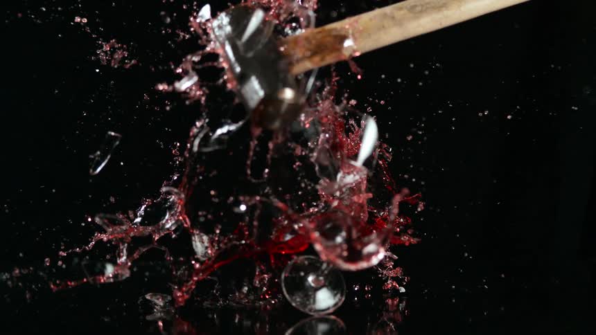Sledgehammer smashing full wine glass in slow motion