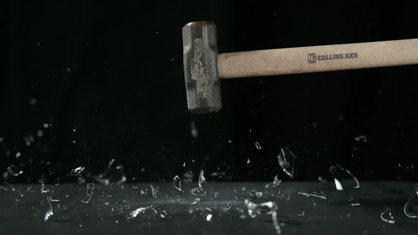 A sledge hammer shatters a wine glass