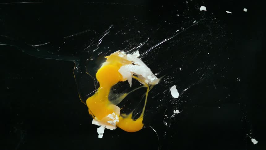 A person throws an egg in front of a back drop
