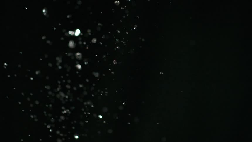 Red strawberries are tossed up in the air and water droplets fall