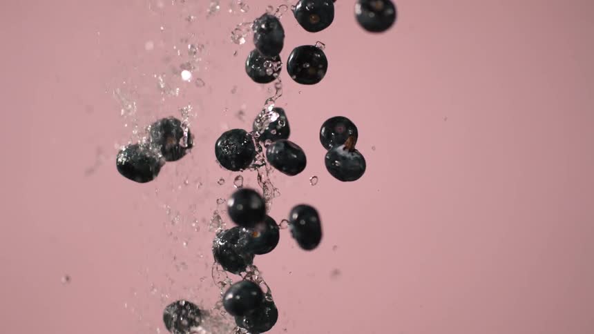 Water is being splashed along with blueberries